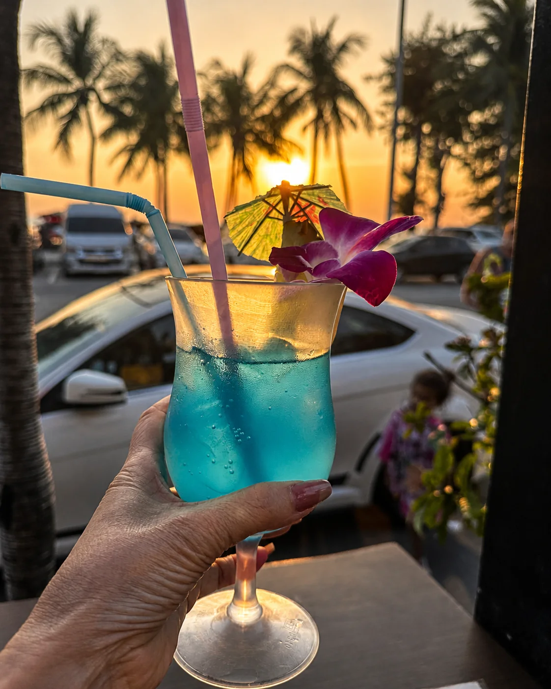 A blue drink held against the Jomtien sunset