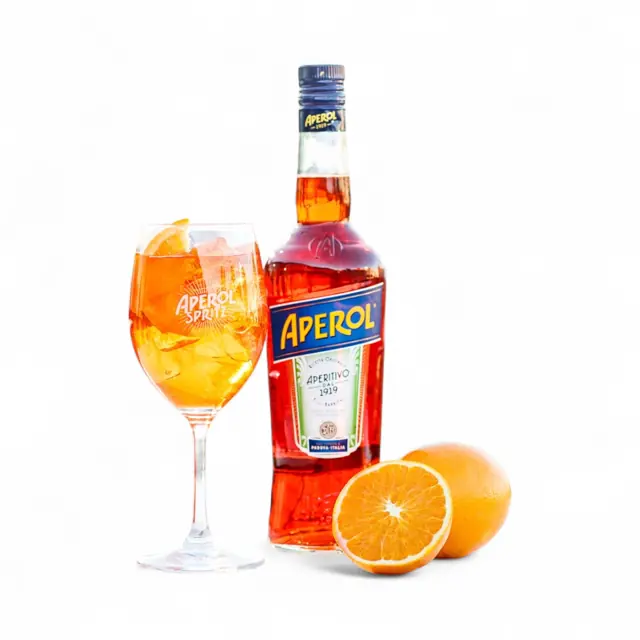 An orange aperitif drink beside a bottle and orange