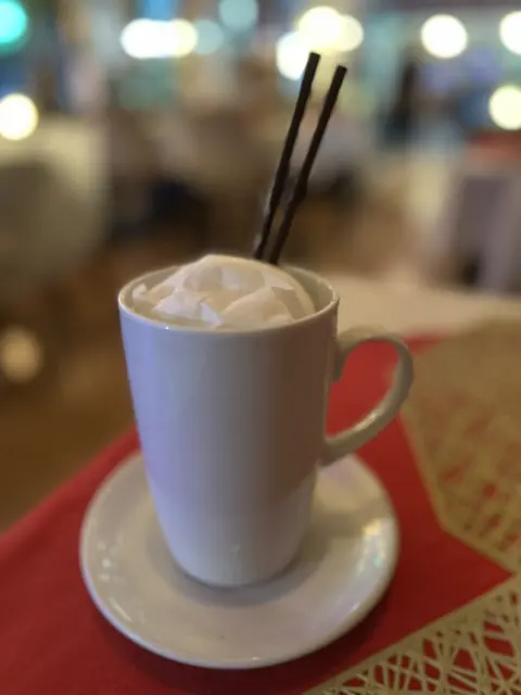 A cup of coffee on a red Sunshine Cafe coaster
