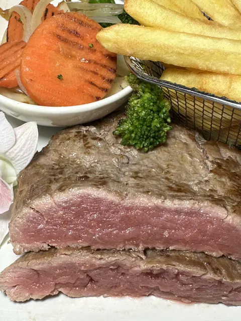 A close view of pepper steak, fries and sauce
