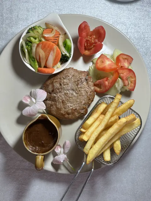 A steak plate with fries, salad and sauce