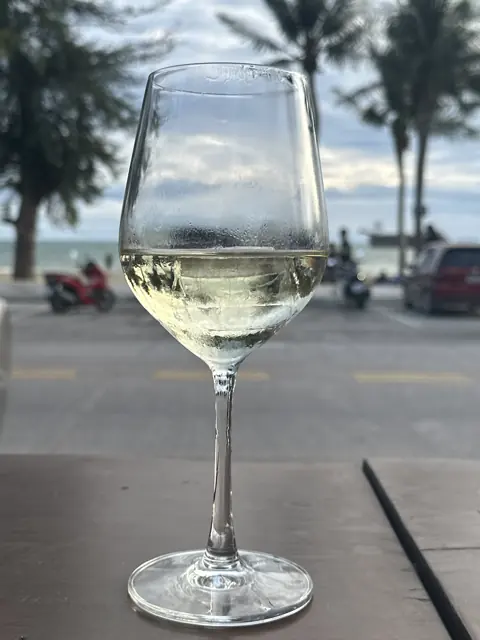 A glass of white wine with Jomtien Beach beyond